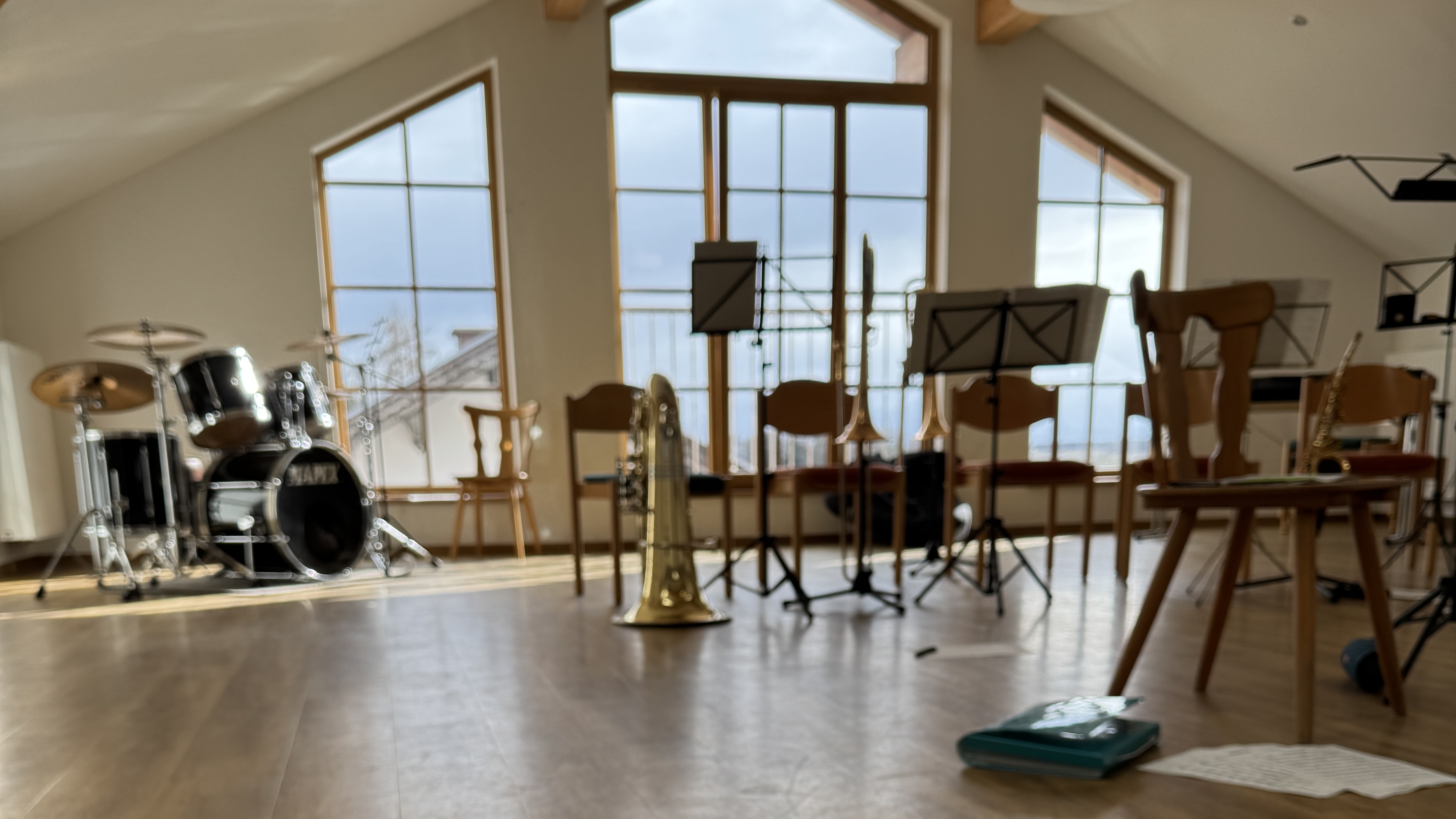 lichtdurchfluteter Probenraum mit Instrumenten und Notenständern ohne Personen, mit einem Notenblatt im Vordergrund