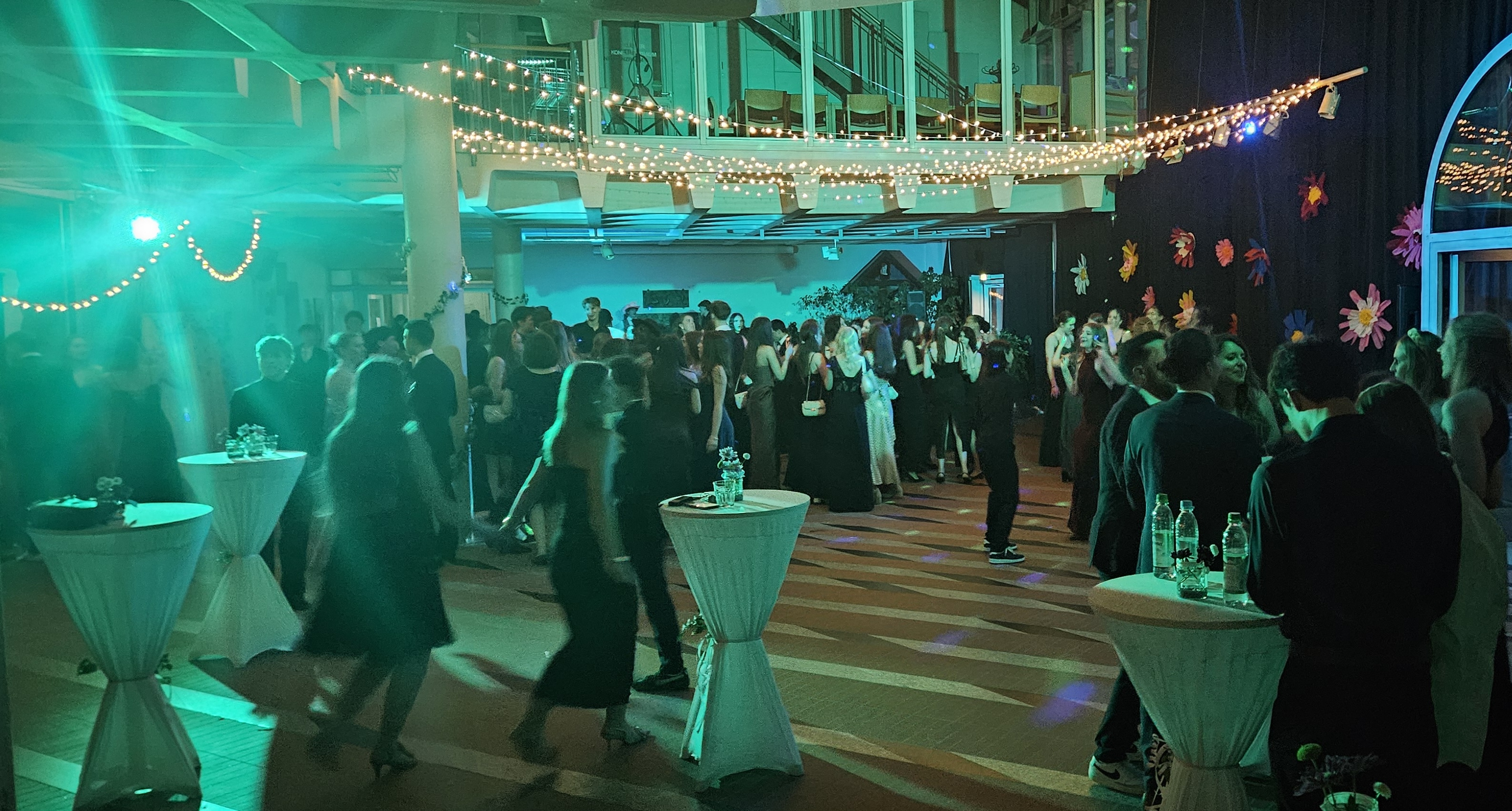 Bild mit Lichterkette und tanzenden Gästen in der Aula